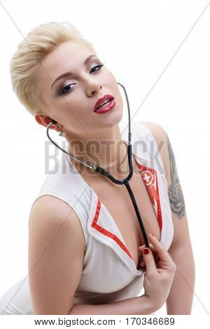 Slim blonde with sexy short haircut in nurse style slinky white dress with phonendoscope studio portrait