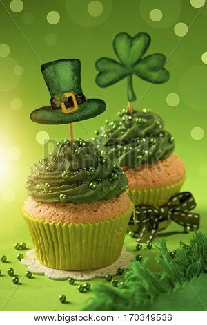 Cupcake with clover cakepick on a wooden background