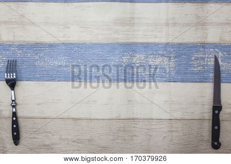 Knife, fork lying on a light wood background of the table. Provence style wooden table, background for menu, bistro, cafe, restaurant