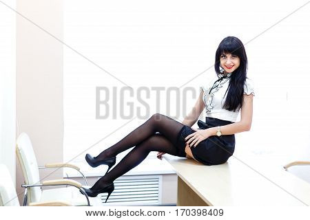 Young sexy woman in black stockings sitting ona table in the office