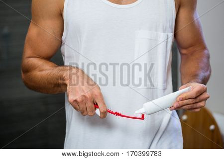 Close-up of man squeezing toothpaste on toothbrush