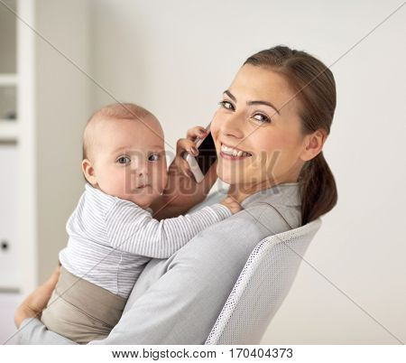 business, motherhood, multi-tasking, family and people concept - happy smiling businesswoman with baby calling on smartphone at office