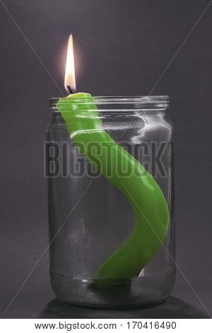 green burning candle in a glass jar