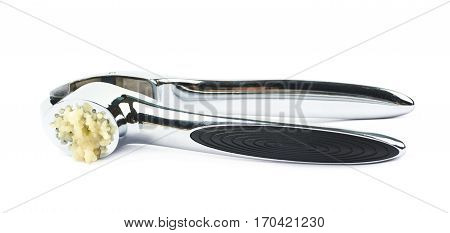 Used metal garlic press utensil with a crushed clove, composition isolated over the white background