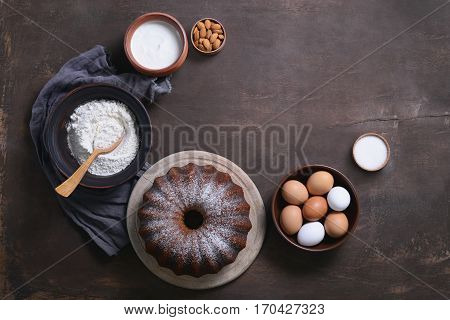 Bundt cake ingredients moody bakery background with aspace for a text top view