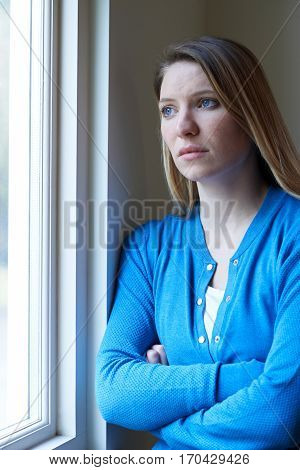 Sad Woman Suffering From Depression Looking Out Of Window