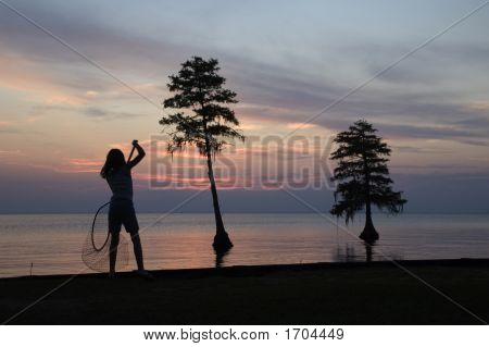 Fische mit einem Netz gegen einen schönen Sonnenuntergang fangen Mädchen