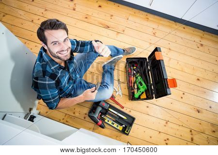 Portrait of man fixing kitchen sink giving thumbs up in the kitchen