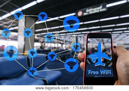 Hand using Smartphone and is using free wifi with wifi icon connection concept  at the airport on blurred background of passengers waiting bording at airport, color tone effect.