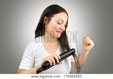 happy woman using flat iron to straigh her hair