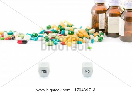 various capsules tablets and container with yes or no dices in front of them isolated on white background.yes or no conceptual photo with medicines and copyspace.