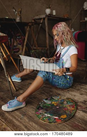 Stylish artist in stained clothes draws in the studio