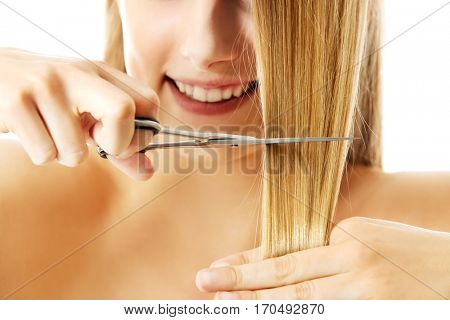 Attractive young woman is cutting her long natural hair