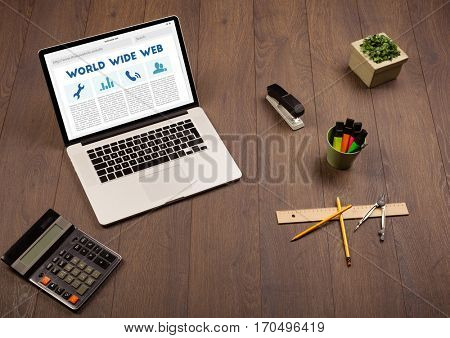 Laptop computer on wooden desk with office suplies