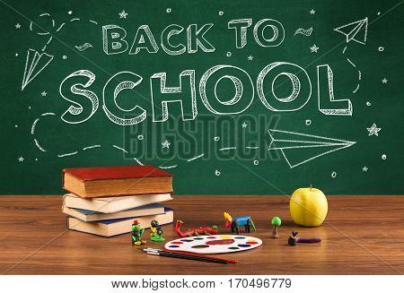Back to school concepty with writing on blackboard and desk, apple, books, items