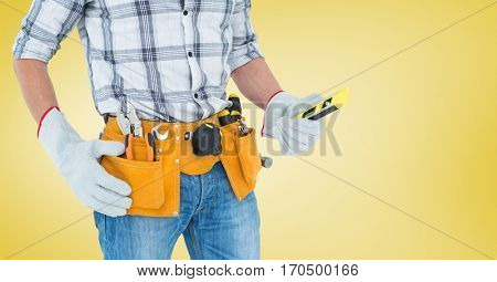 Mid section of handyman with tool belt and spirit level against yellow background