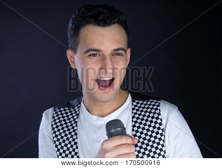 Young Male Black-haired Pop Singer Sings To Microphone