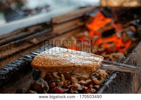 Luleh kebab (minced meat on spits, Middle Eastern staple) being fried on charcoal grill