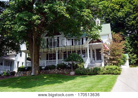 HARBOR SPRINGS, MICHIGAN / UNITED STATES - AUGUST 4, 2016: A large Victorian home with a wraparound porch below the bluff on Fourth Street in Harbor Springs, Michigan.