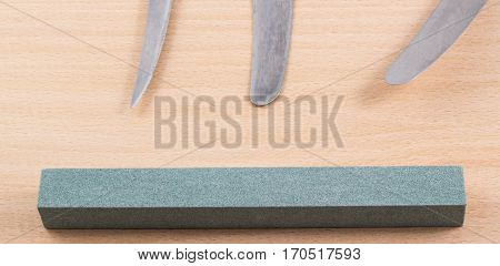 grindstone and blade kitchen knives on a wooden background, what we use every day in the kitchen