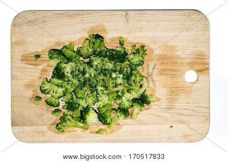 Fresh green broccoli on light brown wooden cutting board close up isolated on white background