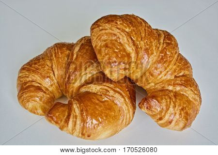 Two croissants on the white plate on the white table