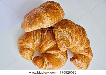 Three tasty croissants on the white table