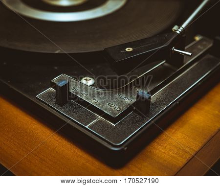 Close up of vintage record player showing stylus cartridge and speed selector