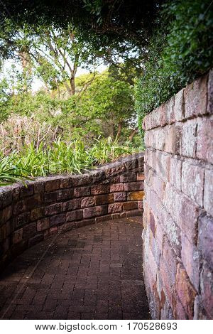 Old brick walls following curved path with overhanging trees