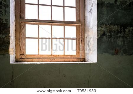 Timber window in abandoned building with wall of peeling paint