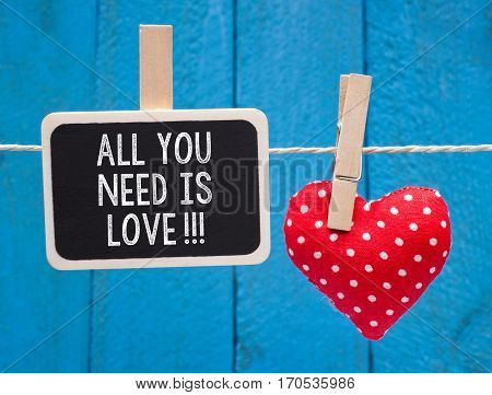 All you need is Love - little chalkboard with text and red heart on blue wooden background