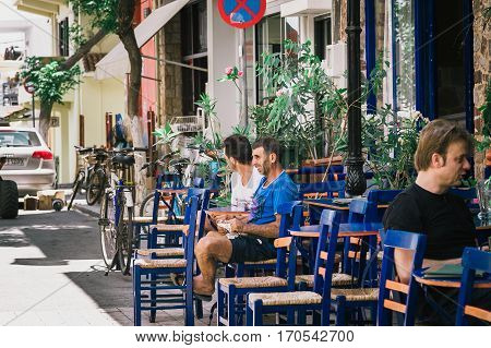 PALEOCHORA, CRETE, GREECE - JUNE 2016: Men are sitting at traditional Greek tavern at Paleochora town on Crete island