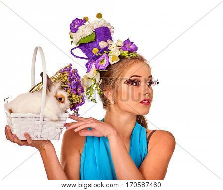Easter girl holding bunny and eggs. Woman with holiday hairstyle and make up holding rabbit in basket with flowers. White background. Makeup with false eyelashes.