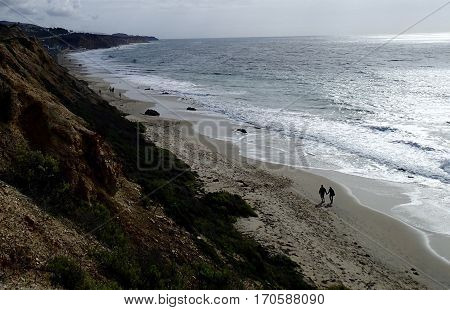 Happy couple walks hand in hand along the beach