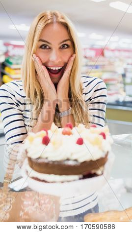 Happy woman with mouth open in front of cake qt grocery store