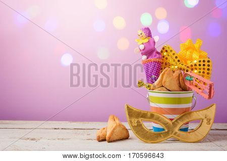 Purim holiday concept with carnival mask and gifts over bokeh lights background