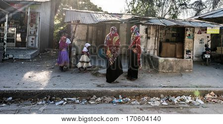 Zanzibar, Tanzania - July 14, 2016: Local folk of Zanzibar, muslim women in burkas and their kids, poor living