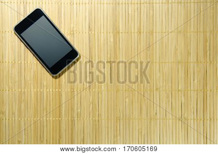 Black Smart Phone on The Bamboo Background. Use for Texture and Wallpaper.