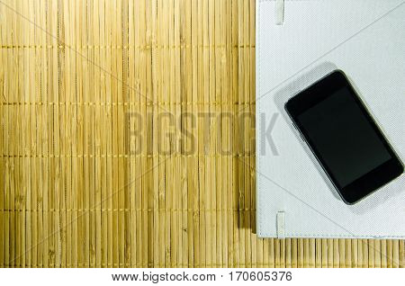 Black Smart Phone on The Bamboo Background. Use for Texture and Wallpaper.
