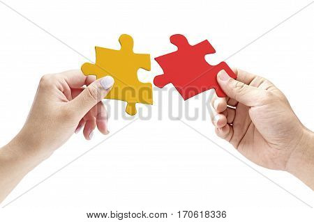 hands of a male and female putting together two matching jigsaw pieces isolated on white background.