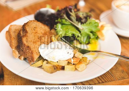 Eggs potatoes lettuce toast and coffee in a breakfast meal spread. Upscale cafe setting.