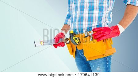 Mid section of handyman with tool belt and spirit level against grey background