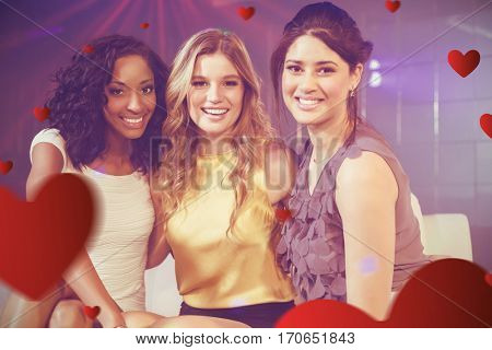 Friends sitting ohn sofa at disco against hearts