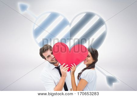 Couple smiling at camera holding a heart against grey background