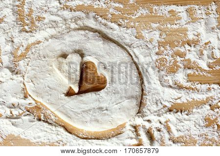 blank heart shape of farinaceous dough on a wooden table / cooking pastry for the holiday