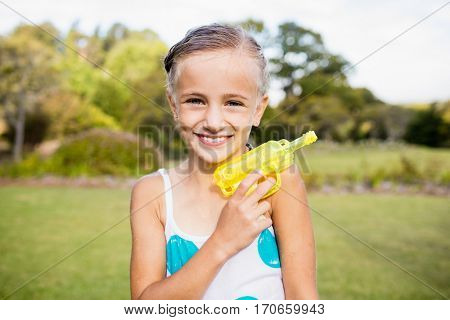 Kid posing at camera during a sunny day with her water gun at park