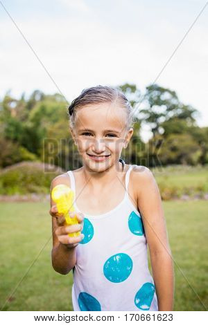 Kid posing at camera during a sunny day with her water gun at park