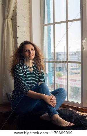beautiful young girl sits on the window