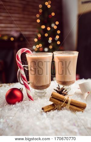 close up view of composite image of hot chocolates against Christmas tree background