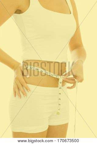 Mid section of woman measuring waste with measuring tape